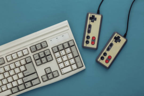 istock Old keyboard and old-fashioned gamepads on a blue background. Retro gaming. 80s. Top view. Flat lay 1312307407