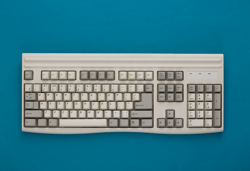 Old pc keyboard on blue background. Top view. Flat lay