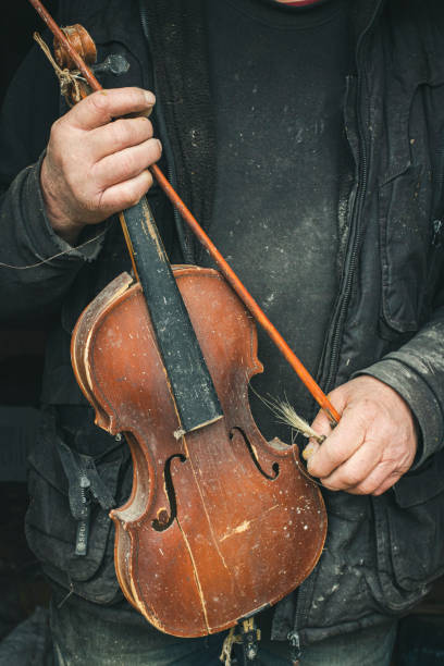 istock Old violin in the hands of a homeless master 1312307876