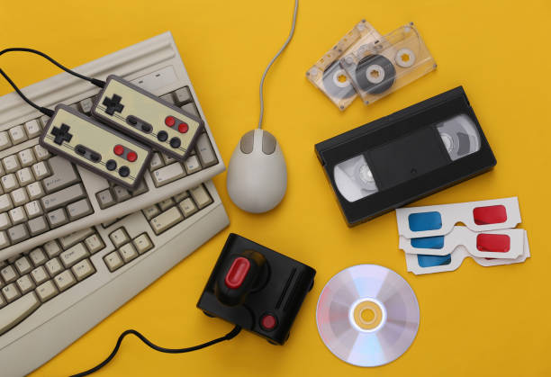 istock Flat lay 80s attribute composition. PC keyboard, mouse, gamepads, audio and video tapes, CD, 3D glasses. Retro Electronics, gadgets and devices. Entertainment and gaming. Yellow background. Top view 1312308704