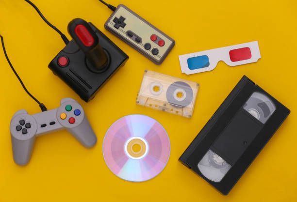istock Flat lay 80s attribute composition. Gamepads, audio and video tapes, CD, 3D glasses. Retro Electronics, gadgets and devices. Entertainment and gaming. Yellow background. Top view 1312308941