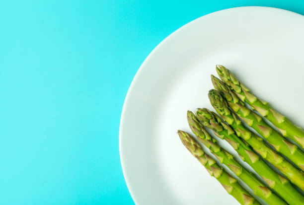 Asparagus on a white plate on a blue background. Fresh vegetable asparagus for a healthy diet and nutrition. Vegetables and healthy food concept Asparagus on a white plate on a blue background. Fresh vegetable asparagus for a healthy diet and nutrition. Vegetables and healthy food concept. High quality photo asparagus organic dinner close to stock pictures, royalty-free photos & images