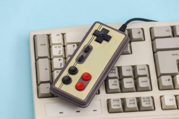 istock Retro gamepad on old pc keyboard. Blue background. Attributes 80s, gaming 1312309429