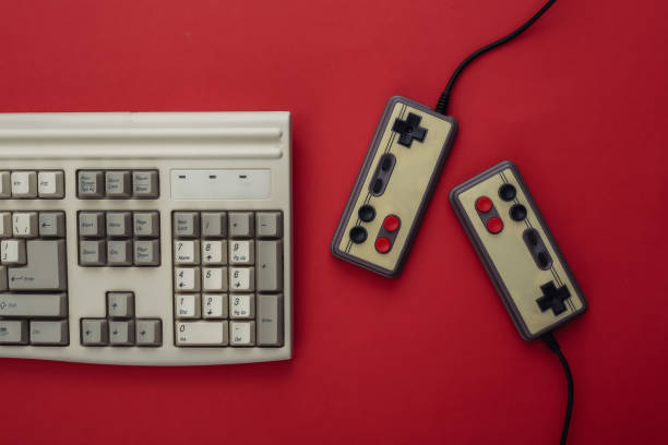 istock Two retro gamepads and old pc keyboard on red background. Gaming, video game competition. Top view 1312309437