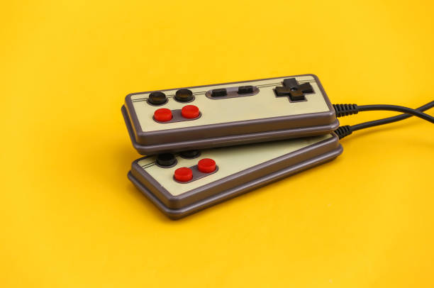 istock Two retro gamepads on yellow background. Gaming, video games. 1312309438