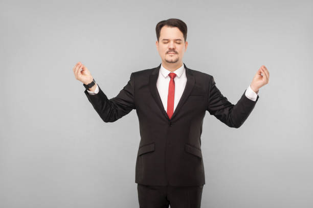 istock Business man closed eyes, standing and doing yoga pose 1312310299