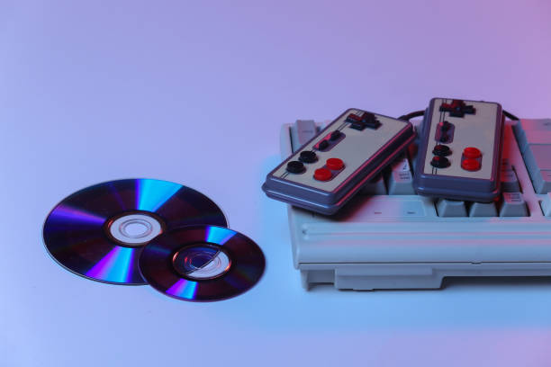 istock Old pc keyboard with gamepads, CD's in pink blue gradient neon, holographic light. Retro Attributes 80s 1312310524