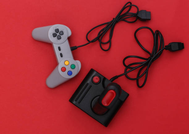 istock Wired retro gamepad and joystick with wound cable on red background. Video game, gaming. Top view 1312310591
