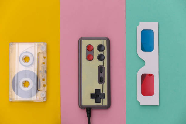 istock Wired retro gamepad, anaglyph 3D glasses and CD's on colored background. Retro Attributes. Top view 1312310606