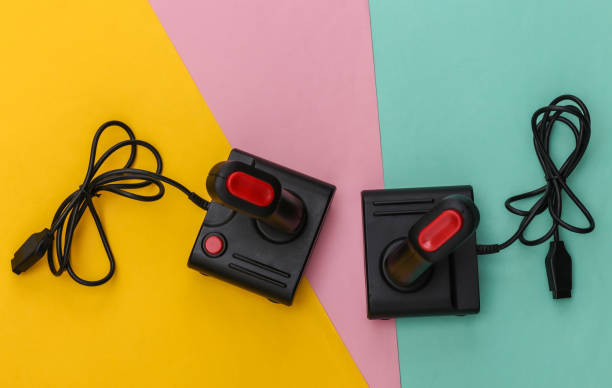 istock Two wired retro joysticks with wound cable on colored background. Video game, gaming. Top view 1312310627