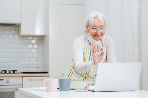 istock An elderly woman waves while, greeting and chatting via video call in a laptop. 1312310730