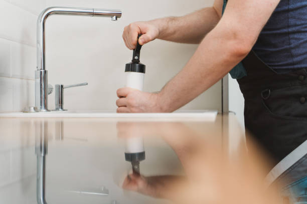 istock Plumber unclogging kitchen sink with professional force pump cleaner. 1312311875