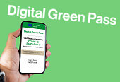 The digital green pass of the european union with the QR code on the screen of a mobile held by a hand with a blurred airport in the background