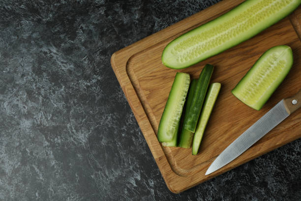 istock Board with ripe cucumber and knife on black smokey table 1312312598