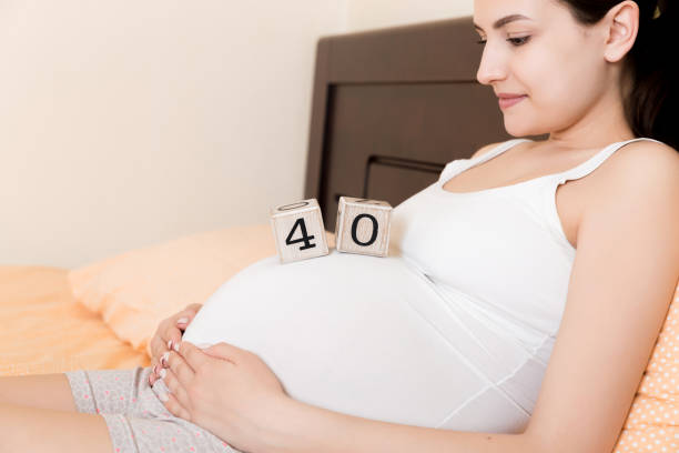 donna incinta in biancheria intima bianca a letto a casa che tiene il calendario con settimane 40 di gravidanza. concetto di maternità. in attesa di un bambino imminente - 40 weeks foto e immagini stock