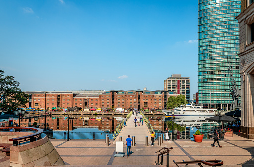 London, UK - August 23 2019: View of the West India Quay, the North Dock and the North Dock pedestrian bridge in Canary Wharf Estate. The warehouse at West India Quay was used to store imported goods from the West Indies, such as tea, sugar and rum, and is now a Grade 1 listed building.