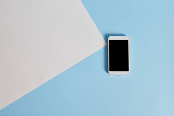 istock High angle view of a white blank paper sheet and smartphone on blue background with copy space 1312313827