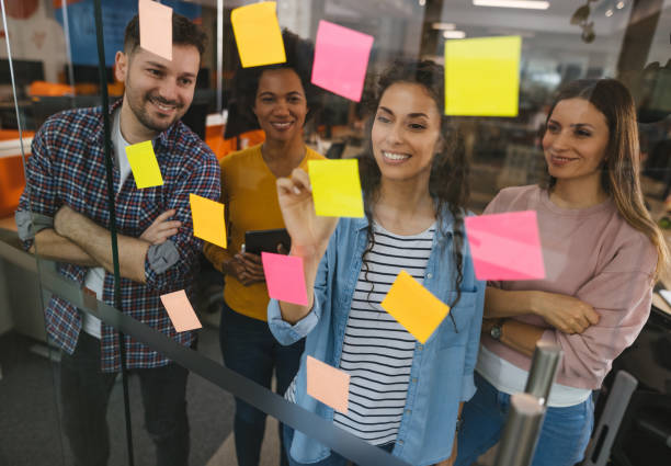 istock Group of web designers using sticky notes on a glass wall during a meeting 1312315163