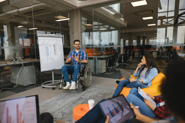 istock Programmer in a wheelchair discussing business moments in a modern office 1312315457