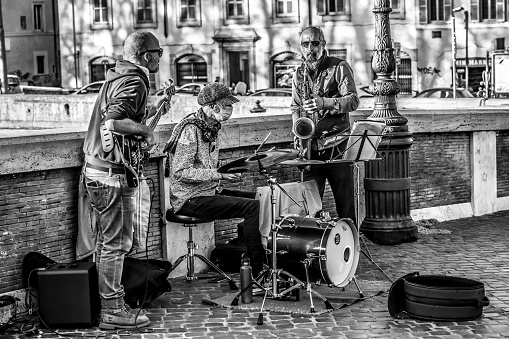 Rome, Italy, April 09 -- A group of street musicians play along Ponte Sisto, in the ancient Trastevere district, at the time of Covid-19. Trastevere is one of the most iconic district of the eternal city, for the presence of monuments and ancient churches, but also for small squares and alleys where it is easy to find typical restaurants, pubs and little store. Image in High Definition Format.