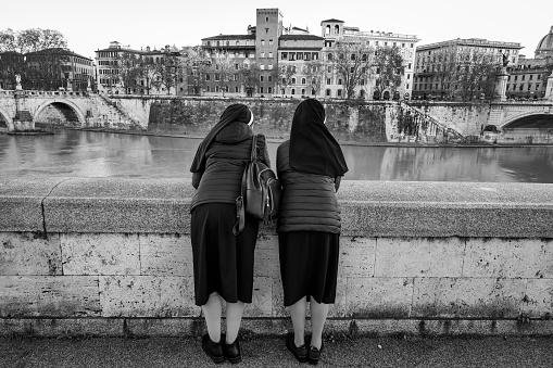 Rome, Italy, December 13 -- A couple of Catholic nuns look out from the balustrade of the Tiber river bank in the historic center of Rome near the Vatican, admiring the panorama of the Eternal City. Image in High Definition format.