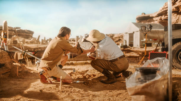 istock Archaeological Digging Site: Two Great Archeologists Work on Excavation Site, Carefully Holding Newly Discovered Ancient Civilization Cultural Artifact, Historical Clay Tablet, Fossil Remains 1312318063