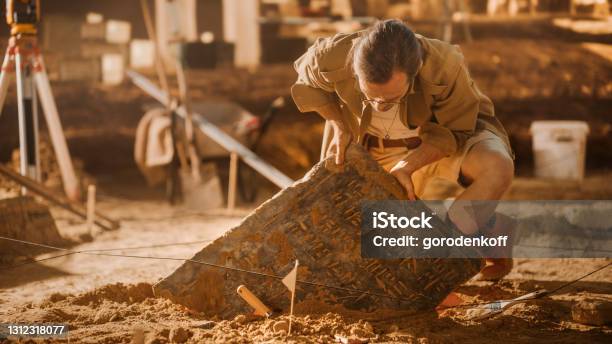 Archaeological Digging Site Great Male Archeologist Work On Excavation Site Carefully Cleaning Lifting Newly Discovered Ancient Civilization Cultural Artifact Historic Clay Tablet Fossil Remains Stock Photo - Download Image Now