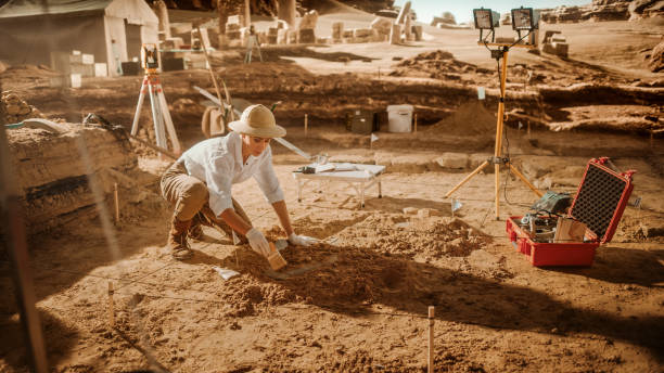 istock Archaeological Digging Site: Great Female Archeologist Work on Excavation Site, Cleaning Cultural Artifacts with Brush and Tools. Discovery of Ancient Civilization Temple, Architecture, Fossil Remains 1312318118