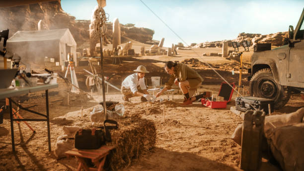 istock Archaeological Digging Site: Two Great Archeologists Work on Excavation Site, Cleaning Cultural Artifacts with Brush and Tools. Discovery of Ancient Civilization Temple, Architecture, Fossil Remains 1312318121