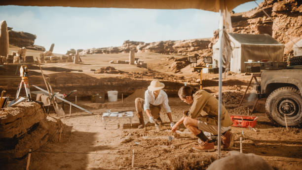 istock Archaeological Digging Site: Two Great Archeologists Work on Excavation Site, Carefully Cleaning with Brushes and Tools Newly Discovered Ancient Civilization Cultural Artifacts, Fossil Remains 1312318122
