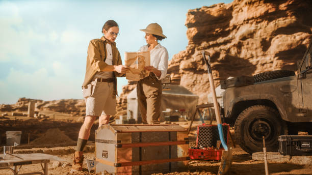 istock Archaeological Digging Site: Two Great Archeologists Work on Excavation Site, Use Map to Inspect Newly Discovered Ancient Civilization Architectural Site, Planning Work 1312318147