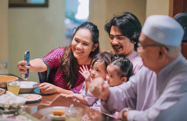 ramadan hari raya malaysian muslim multi generation family videocall relative enjoying dinner at home in dining room