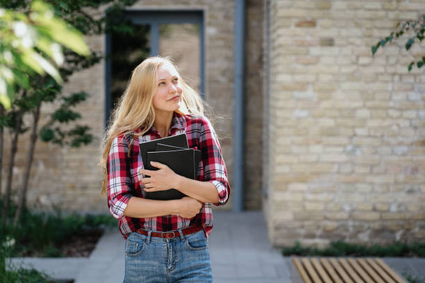 istock Young academy student girl looking aside, hugging copybooks 1312326602