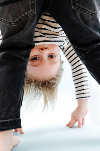 istock Silly little blond boy bending forward, looking between his legs. Over blue 1312326704