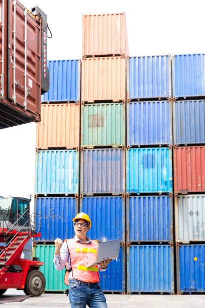 istock Foreman or Operator Ordering of moving containers with laptop computer. Foreman looking forward on Forklifts in the Industrial Container Cargo freight ship. 1312330140