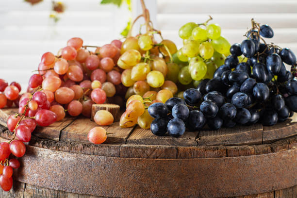 Red, black and green grape on wine barrel.
