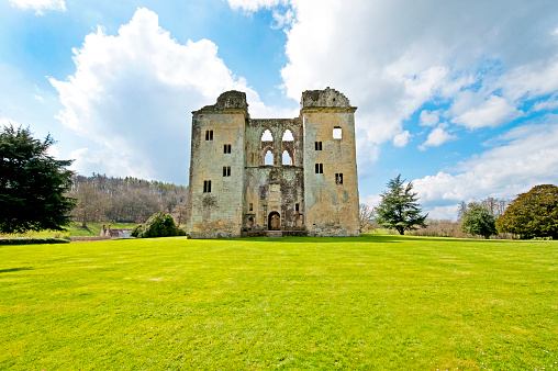 Old Wardour castle near Tisbury, Wiltshire, England. Ancient and medieval stone architecture of Old Wardour castle ruins near Tisbury, Wiltshire, England on a bright sunny April day with blue sky and fluffy cumulus clouds in a green landscape