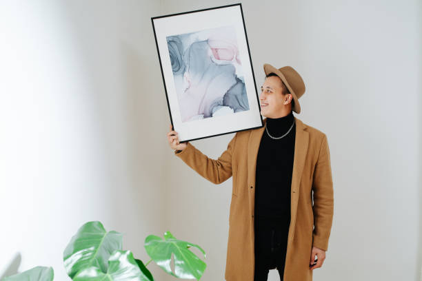 istock Smiling man in beige suit and classical hat posing with painting on his shoulder 1312335128