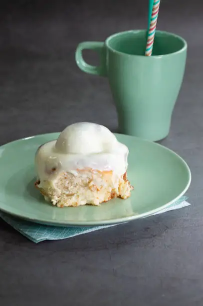 delicious cinnamon-sugar swirl with cream on a green plate and a green cup with a napkin on a dark background