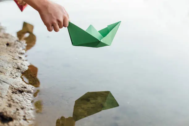 Boy putting Paper Boat into river.