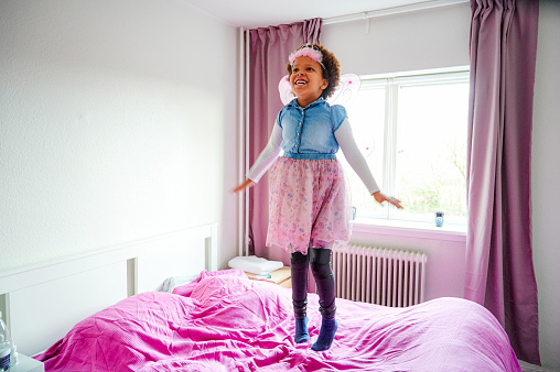 Shot of a little girl wearing fairy wings and a crown while playing in her bedroom