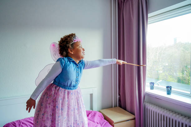 Shot of a little girl wearing fairy wings and a crown while playing with a wooden spoon