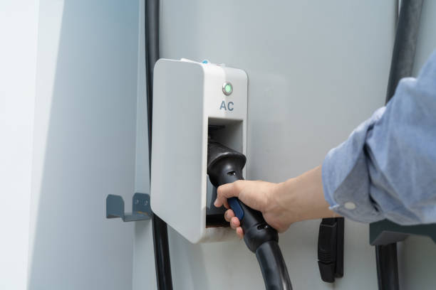 istock Hand pulling in cable from EV car charger or electric vehicle station. Cable connected at gas station, power supply battery charging an alternative eco environment future technology energy innovation 1312343482