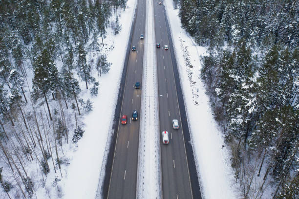 tráfico en una carretera a través de un bosque en invierno - autopista de cuatro carriles fotografías e imágenes de stock
