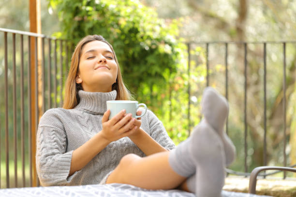 donna rilassata con tazza di caffè appoggiata in un balcone - balcony women patio coffee foto e immagini stock