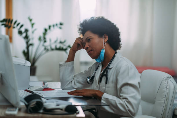 istock Tired female doctor using laptop at doctor's office 1312345982