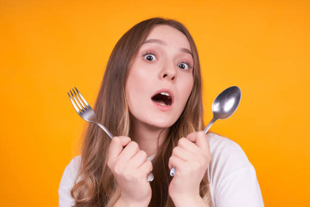 istock Young surprised girl with a fork and a spoon in her hands. 1312348277