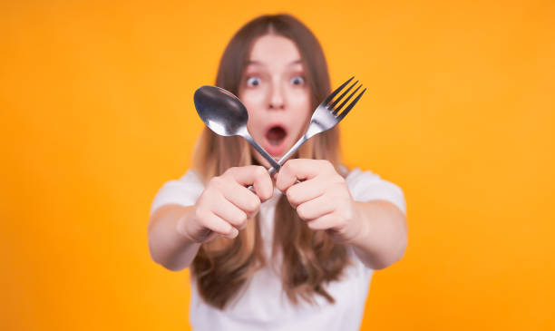 istock Young surprised girl with a fork and a spoon in her hands. 1312348308