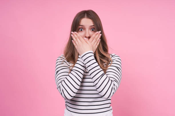 istock Cute beautiful girl covered her mouth with her hands, calling for silence 1312348997