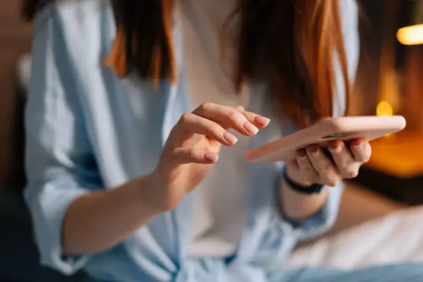 Photo of Close-up of unrecognizable woman texting message on mobile cellphone and chatting on social online.